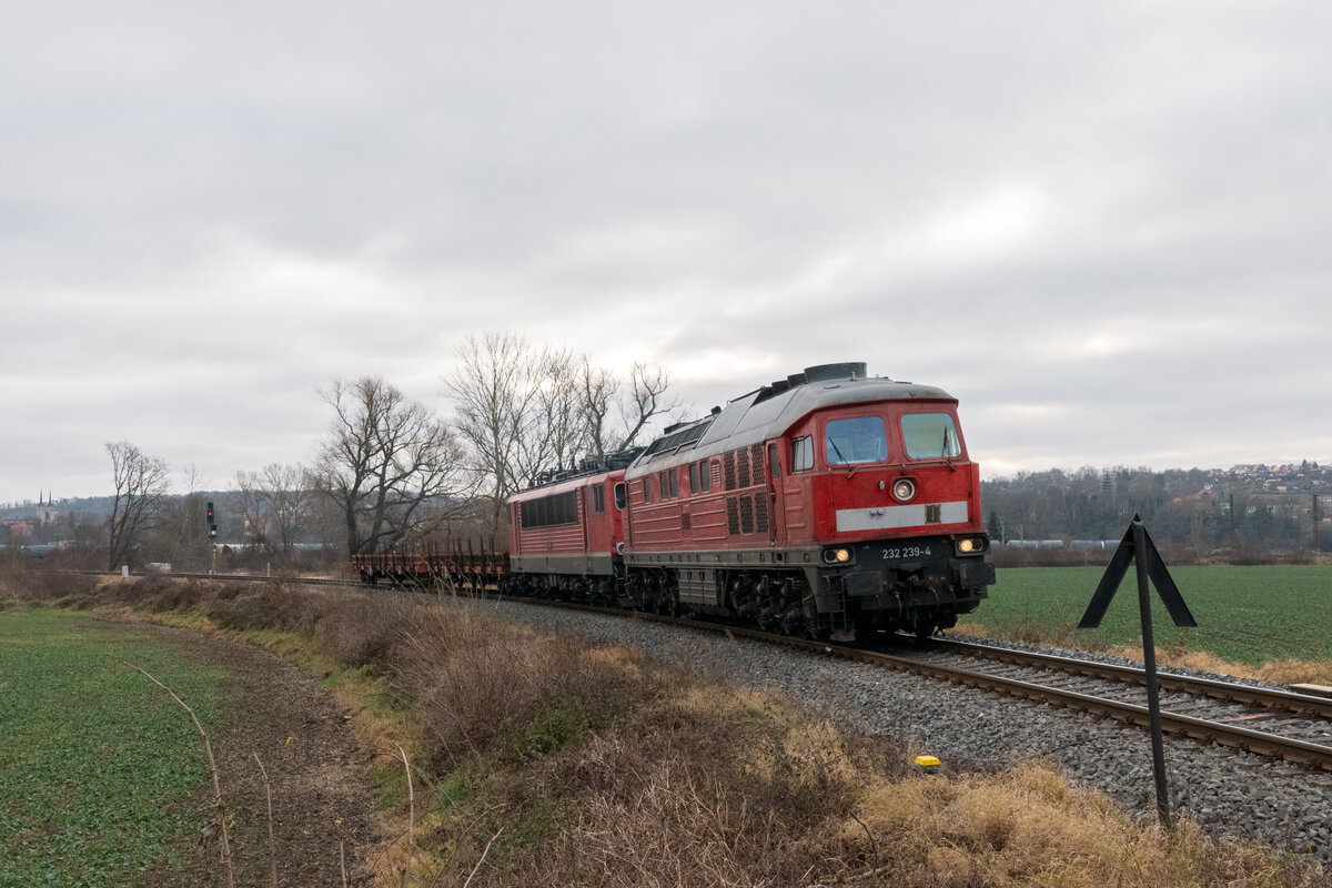 232 239 (EBS) zog am 15.12.2021 155 046 (FWK) und zwei Flachwagen mit anstehender Hauptuntersuchung, bzw. Revision nach Karsdorf. Hier verlässt die illustre Fuhre Naumburg.