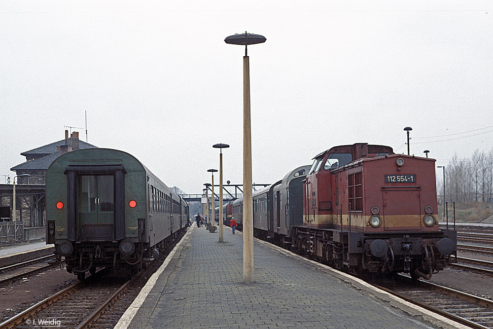 Am 21.03.1991 im Bahnhof Querfurt. Links steht der GmP 68627 aus Röblingen am See, der mit der DR 112 355-3 und dem 1. Wagen als P 16555 nach Vitzenburg weiterfährt. Rechts steht die DR 112 554-1 mit dem P 15554 nach Röblingen und direkt dahinter erkennt man noch die DR 112 725-7 mit dem P 15538 nach Merseburg. (Foto: Ingmar Weidig)