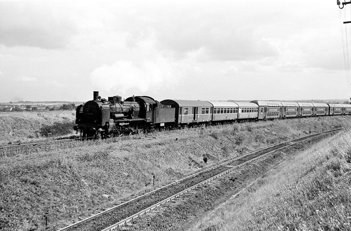 Am 24.08.1966 mit Nachdruck über den Zangenberg.
Hier müht sich 38 3215 mit drei Rekowagen und 2 Vierwageneinheiten Bauart DB13e bei Zeitz über den Zangenberg. Alleine schafft sie es nicht. Damit die Reise für den P 1331 von Zeitz nach Halle (S) Hbf gelingt, schiebt von hinten die 58 453 nach. (Foto: Biesdorfer83)