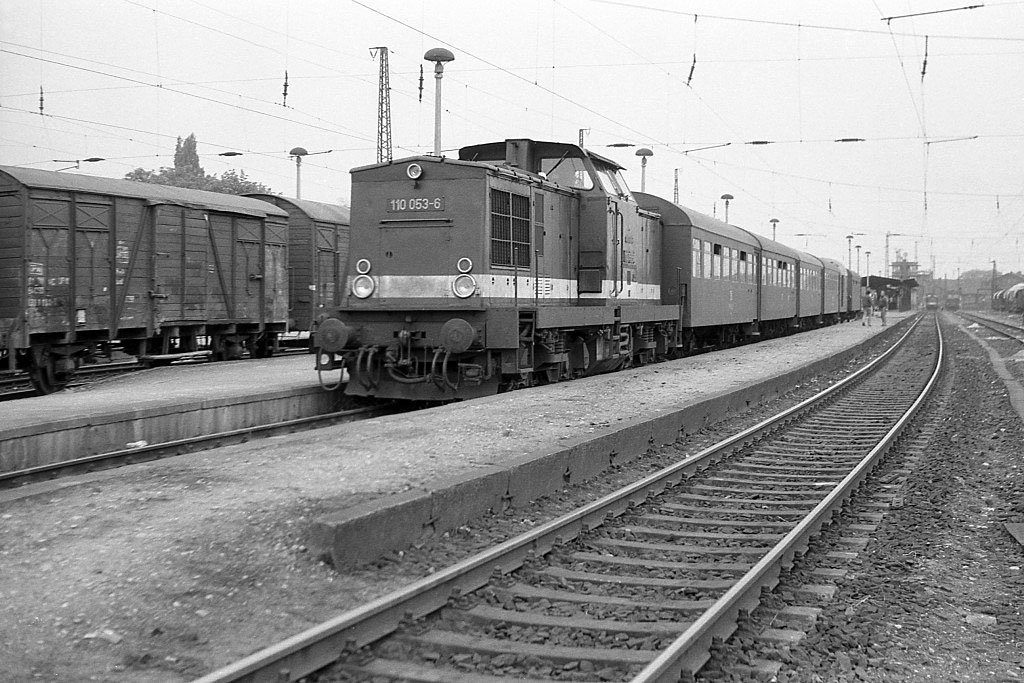 Im Mai 1987 steht am damlals noch vorhandenen Bahnsteig 6 in Naumburg (S) Hbf die 110 053-6 mit P 15089 (Nachmittagszug) nach Teuchern.
Übrigens war dieses Gleis betrieblich Gleis 20. Wie aus dem Bild ersichtlich, besteht der Zug aus 4 Bag-Wagen und einem Packwagen (Daa).
Am Prellbock hinter dem Packwagen steht ein weiterer Bag-Wagen, der nicht zum Zug gehört. Es handelt sich dabei um einen Bag-Wagen, der am Abend zuvor als P 68499 von Naumburg nach Mertendorf verkehrte. Zurück gelangte er ohne Besetzung mit dem letzten Güterzug von der Hochbahn, wo er stets am Schluss eingestellt war. Die Rangierlok  Ostseite  holte ihn dann vom Zug und setzte ihn nach Gleis 20 an den Prellbock, wo er auf seinen nächsten Einsatz am folgenden Tag wartete. Bei den Eisenbahnern war dieser Wagen als sogenannte  Klasse  bekannt. (Foto: Roland Reimer)